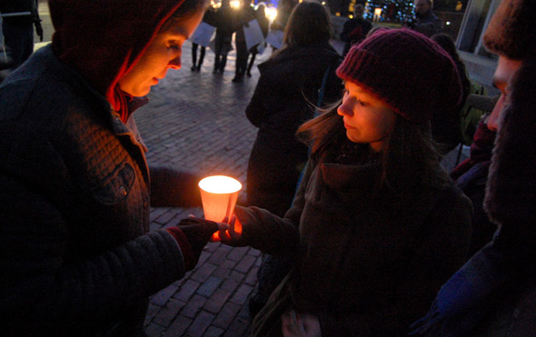 People holding a protest candle in front of the State House
