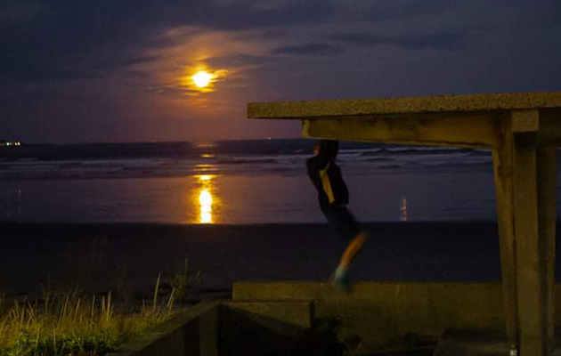 Man doing pullups under a full moon in Lynn