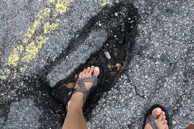 Woman up to her ankle in Jamaica Plain pothole