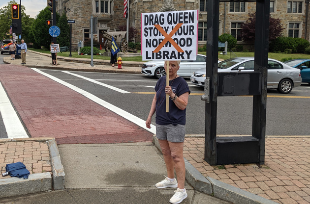 Woman holding sign against drag-queen story hour at the Norwood library