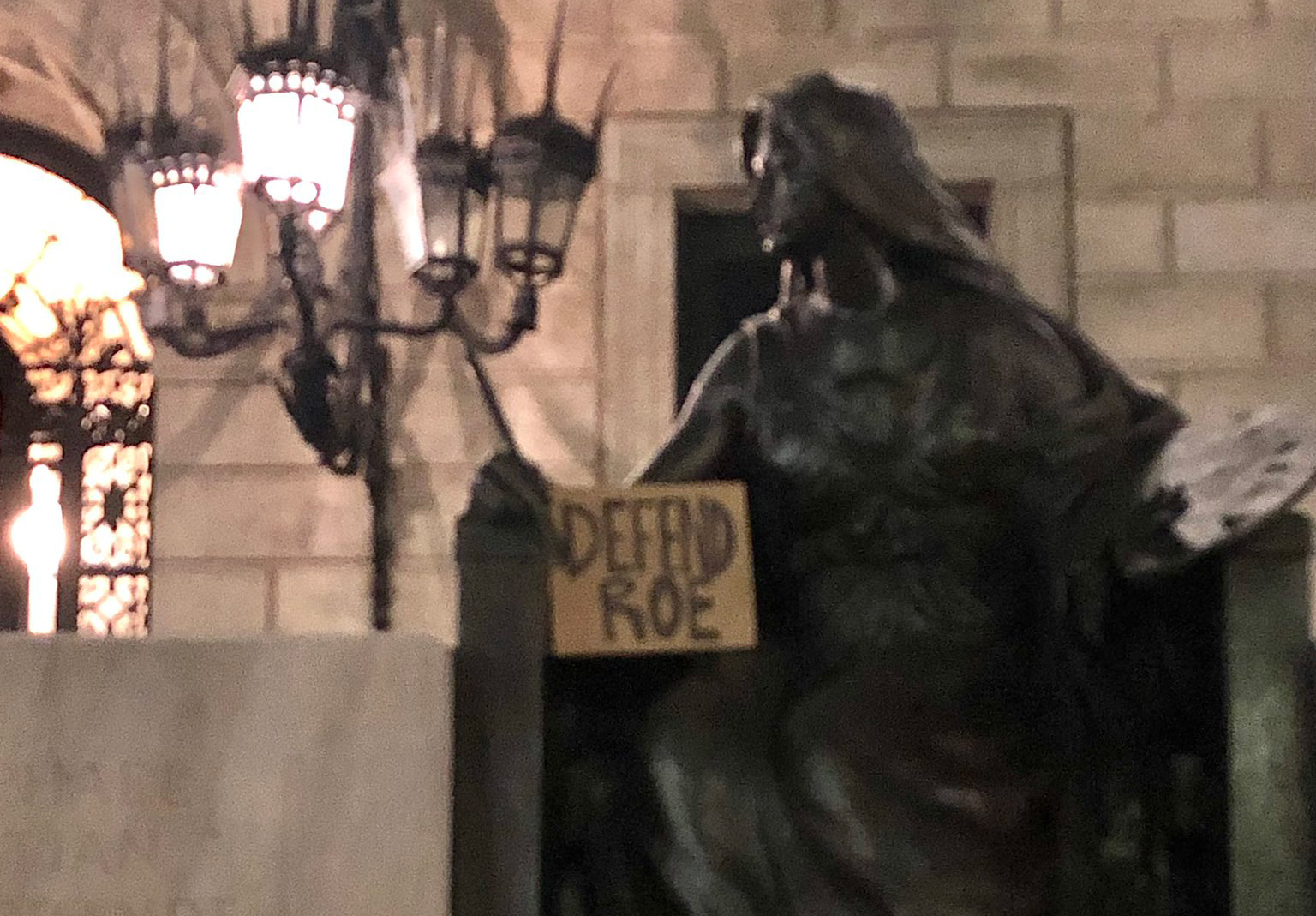 Statue of Art holding a sign reading: Defend Roe
