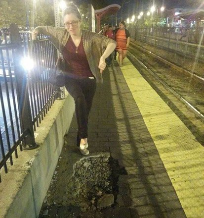 Woman pointing at giant hole at Brighton trolley stop