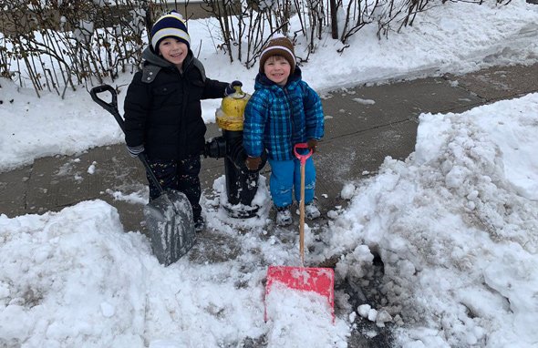 Two kids shovel out a hydrant in Roslindale