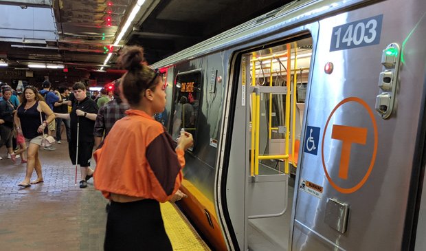 Woman in orange gets on the Orange Line at Forest Hills
