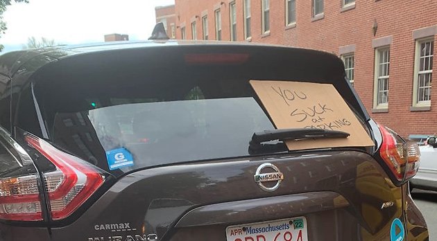 Placard on rear windshield says car owner sucks at parking
