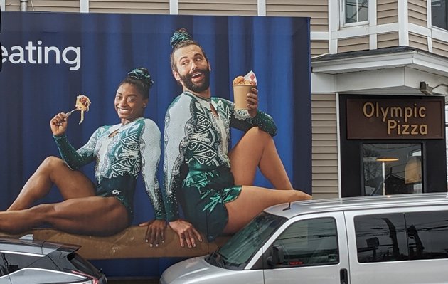 Simone Biles and a Queer Eye guy on the side of Olympic Pizza