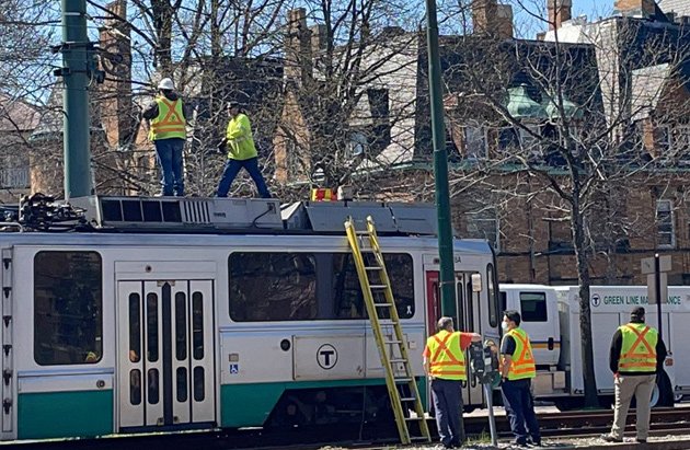 Workers atop a Green Line trolley on Beacon Street