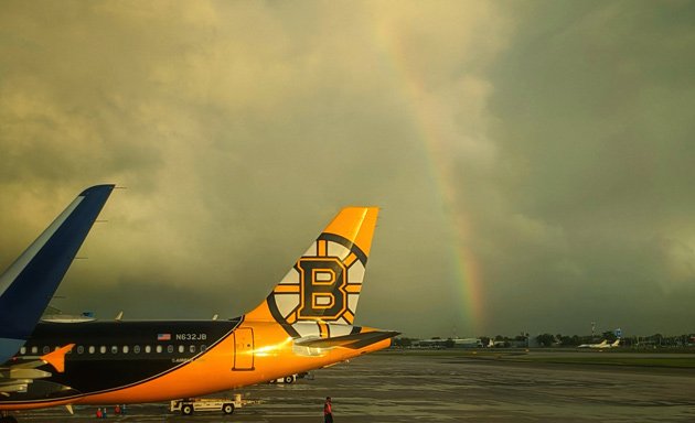 Plain with a Bruins tail in front of a rainbow