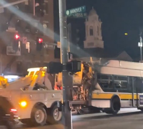 Burned bus being towed past the North End
