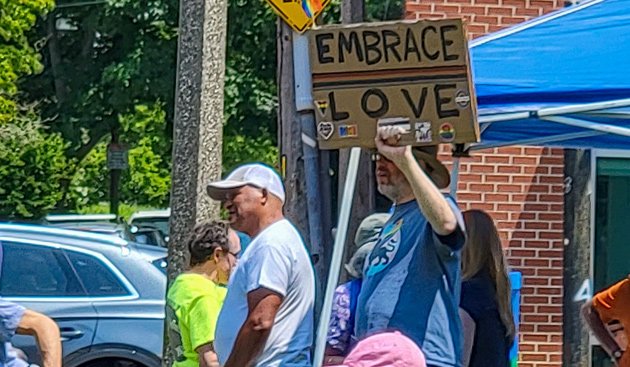 Man with sign reading Embrace Love