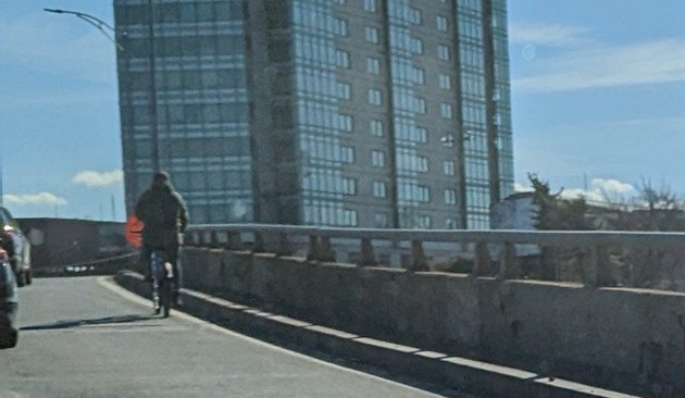 Person riding a Blue Bike onto the turnpike