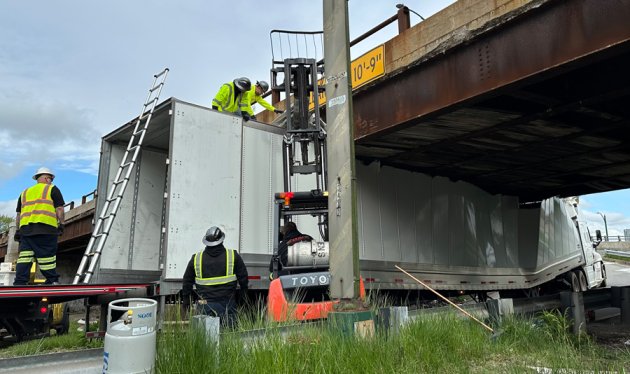 Workers try to figure out how to get trailer out from under overpass