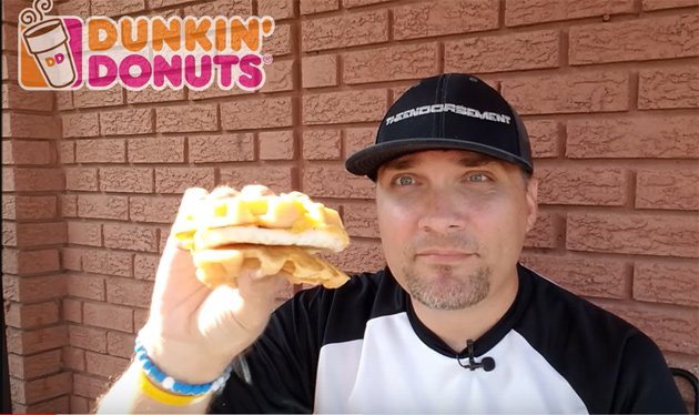 Guy holding a Dunkin' Donuts Belgian Waffle Breakfast Sandwich
