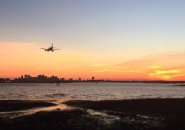 Plane landing at Logan Airport at sunset over Boston Harbor