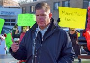 Marty Walsh in front of protest signs