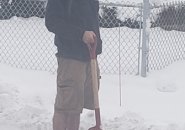 Man shoveling snow in shorts in Watertown