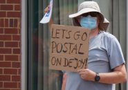 Man with sign that reads: Let's go Postal on DeJoy