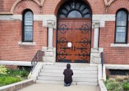 Woman praying outside closed church in Dorchester