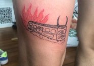 Tattoo showing a devil-horned Orange Line car on fire