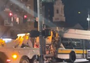 Burned bus being towed past the North End