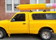 Yellow pickup truck with giant pencil on top