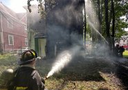 Firefighter aims water at smoldering Thetford Avenue home