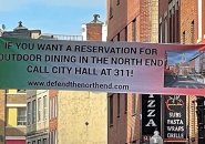 Banner across Salem Street urging people to call 311 to complaint about outdoor patios