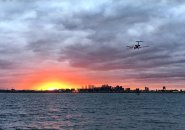 Plane flying into the sunset over Boston Harbor